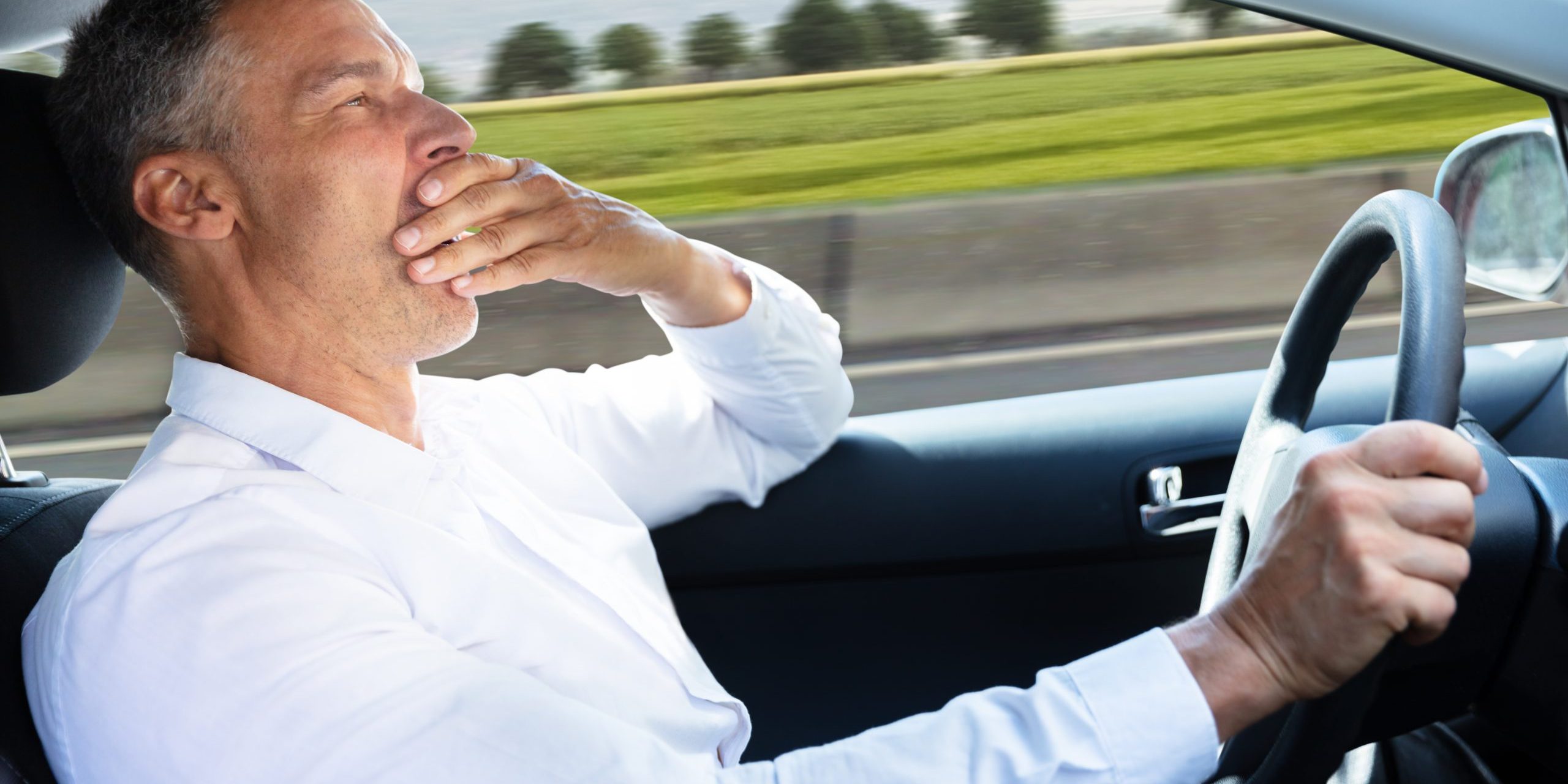 Man Yawning While Driving Car