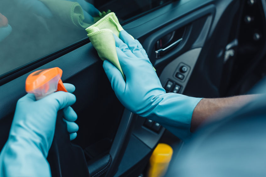 cropped view of car cleaner holding rag and spray bottle while cleaning car door