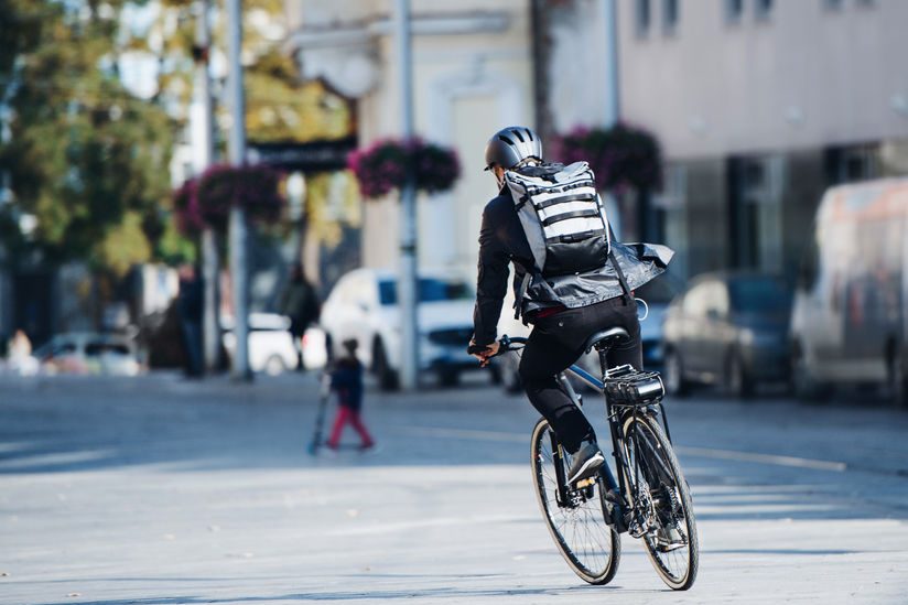 A rear view of male bicycle courier delivering packages in city. Copy space.
