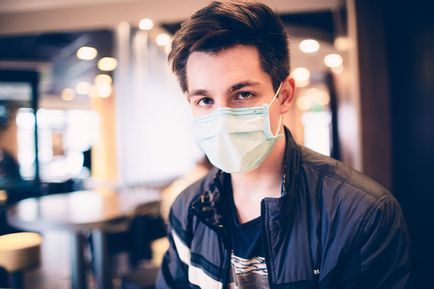 Man wearing medical face mask in the a restaurant. Male wearing face mask, protection from virus infection.