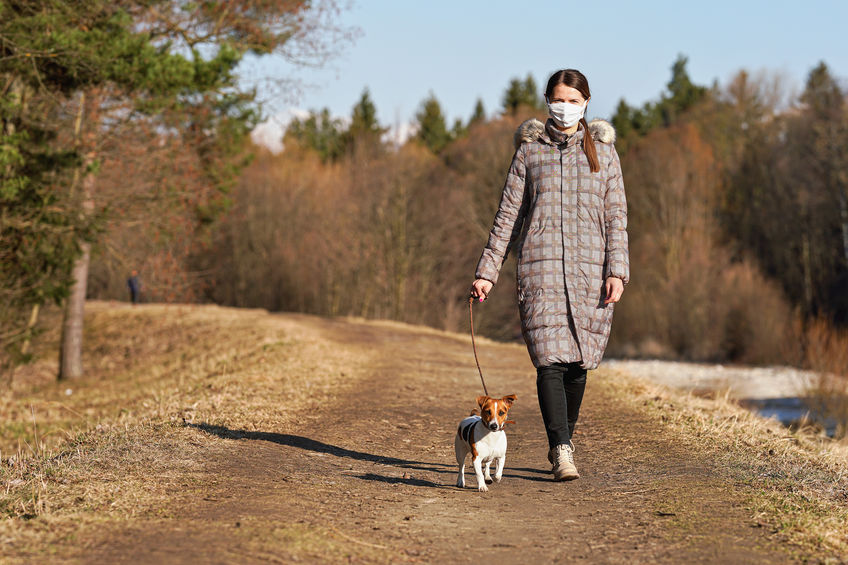 Young woman in warm jacket, wearing virus face mouth mask, walks