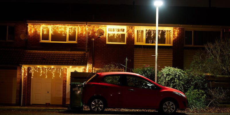 A car sat under the security of a street lamp with Christmas lig