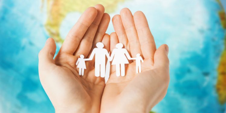 human hands holding paper family over earth globe
