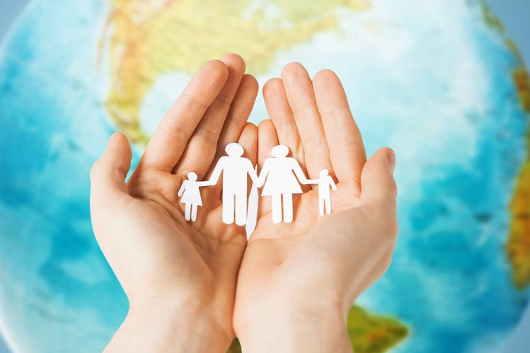 human hands holding paper family over earth globe