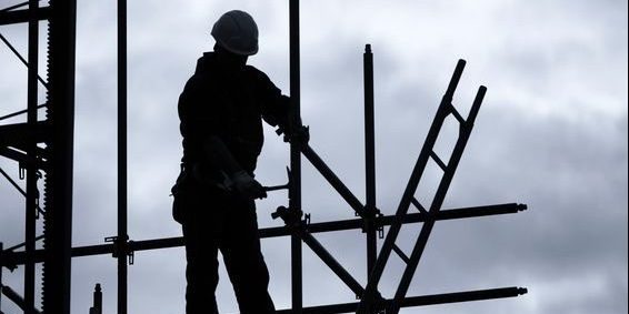 17899629 – silhouette of construction worker on scaffolding, blue toned